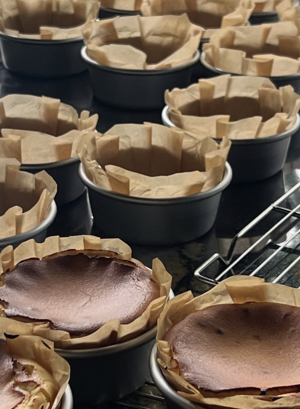 Mini Basque cheesecakes in tins on a cooling rack